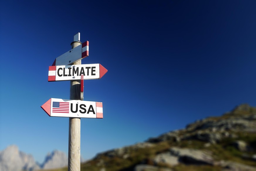 Climate change and American flag in two directions on road sign. Withdrawal of climatic agreement.