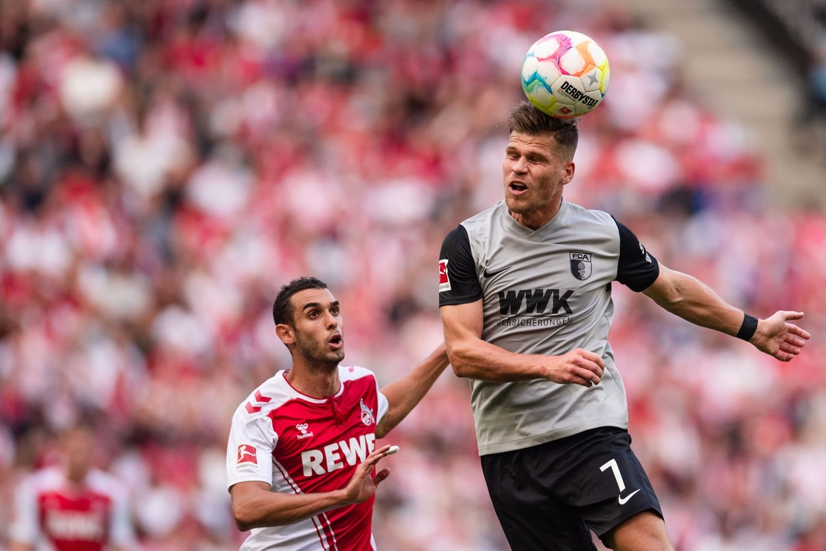 16.10.2022, Nordrhein-Westfalen, Köln: Fußball: Bundesliga, 1. FC Köln - FC Augsburg, 10. Spieltag, RheinEnergieStadion. Augsburgs Florian Niederlechner (r) spielt den Ball. Links Kölns Ellyes Skhiri. ...