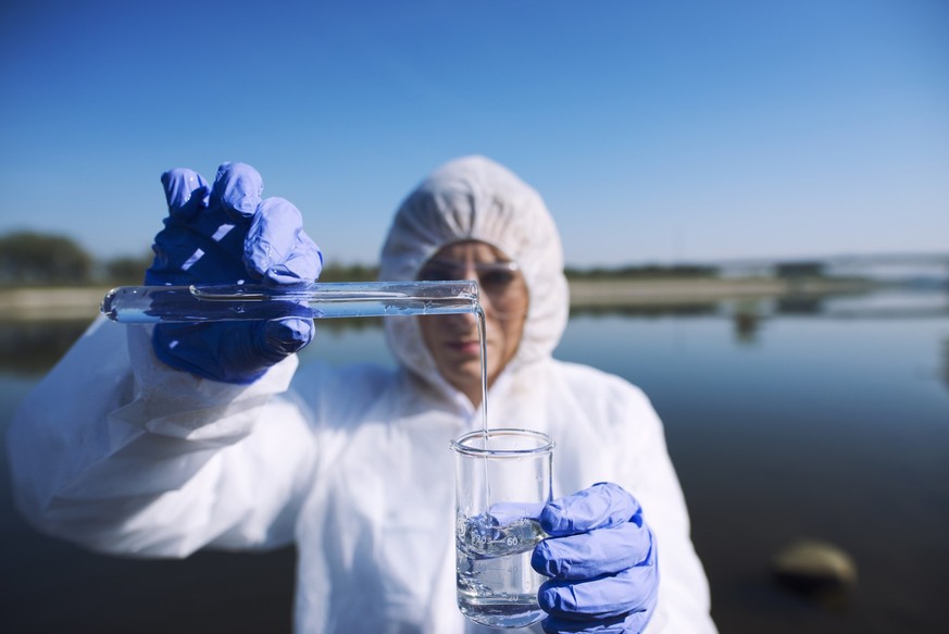 Close up view of ecologist sampling water from the river with test tube. Examining level of pollution. Conserve water and environment.