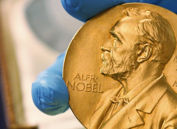 ARCHIV - 17.04.2015, Kolumbien, Bogota: Ein Mitarbeiter der Nationalbibliothek zeigt eine goldene Nobelpreismedaille. (zu dpa