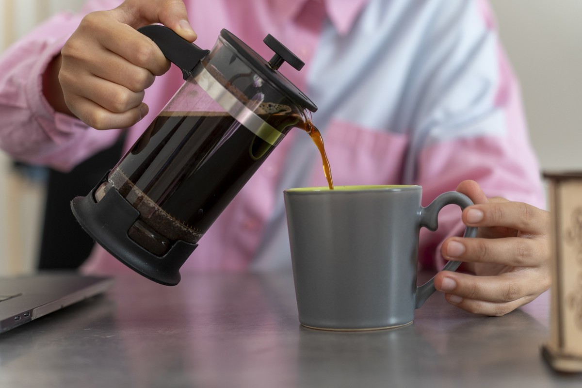 Businesswoman drinking filter coffee at her desk. Brewing filter coffee with a French press.