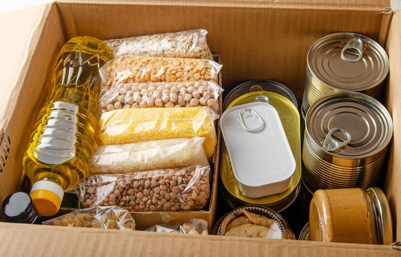 Set of uncooked foods in carton box prepared for disaster emergency conditions or giving away closeup view