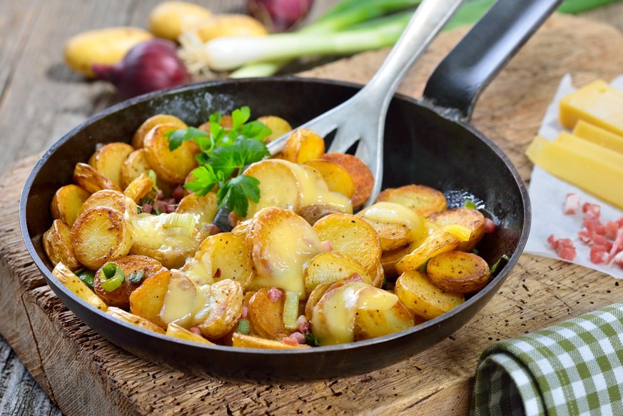 Fried unpeeled baby potatoes with melted mountain cheese and bacon cubes