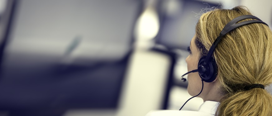 Panoramic shot of a female IT helpline employee next to an LCD screen.