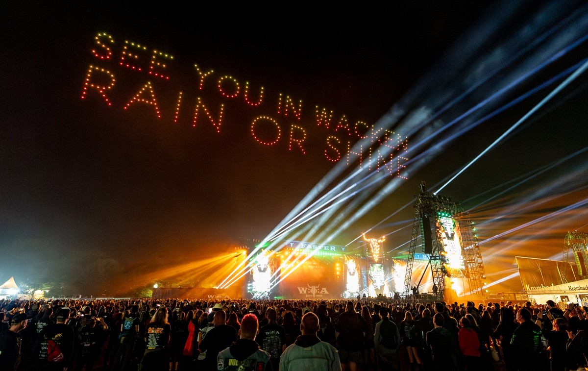 03.08.2024, Schleswig-Holstein, Wacken: Bei einer Drohenshow wird über den Bühnen zum Abschluss des Wacken Open Air das Motto &quot;See you in Wacken Rain or Shine&quot; projiziert. Das WOA gilt als g ...