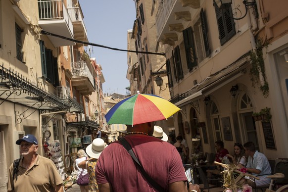 14.07.2023, Griechenland, Korfu-Stadt: Ein Mann schützt sich mit einem Schirmhut gegen die Sonne an diesem heißen Tag in Korfu-Stadt auf der Insel Korfu. Hitze ohne Ende in weiten Teilen Griechenlands ...