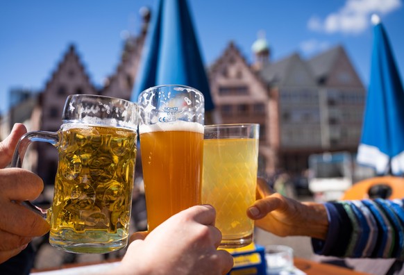 22.09.2022, Hessen, Frankfurt/Main: Drei Besucher stoßen vor der Kulisse des Frankfurter Römers im Sonnenschein mit einem Bier, einem Weizenbier und einem Apfelwein an, einen Tag vor dem kalendarische ...