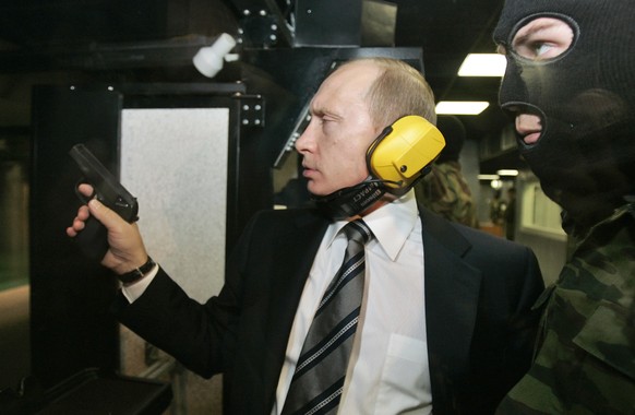 FILE In this file photo taken on Wednesday, Nov. 8, 2006, President Vladimir Putin wears headphones as he tests a pistol in a shooting range as he visits the Defense Ministry&#039;s Main Intelligence  ...