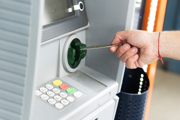 Human hand inserting a credit card into an ATM to withdraw money