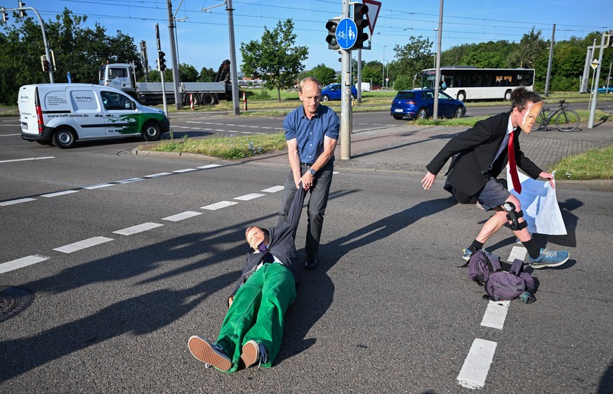14.07.2023, Sachsen, Dresden: Ein Mitglied der Protestgruppe Letzte Generation wird bei einer Sitzblockade an der Autobahnabfahrt am Elbepark von einem Autofahrer (M) beiseite gezogen. Die Demonstrant ...