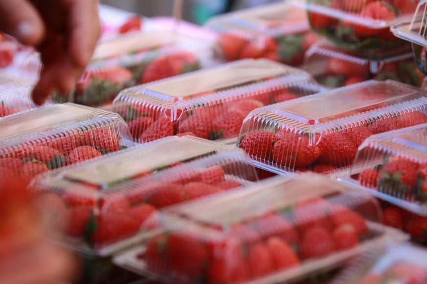Strawberry in plastic packaging for sell and hand of the buyer choose to buy Strawberry