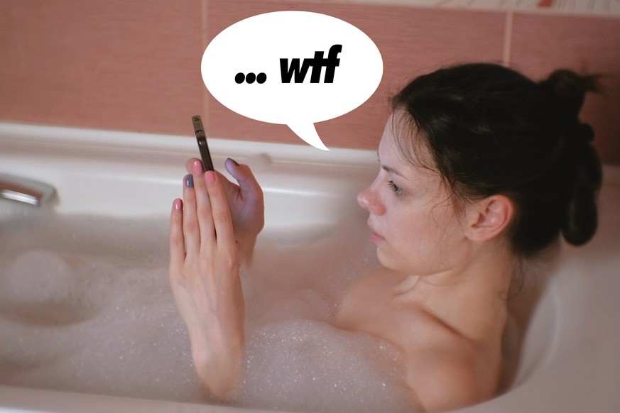 Young beautiful brunette woman takes a bath, browsing internet in mobile phone
