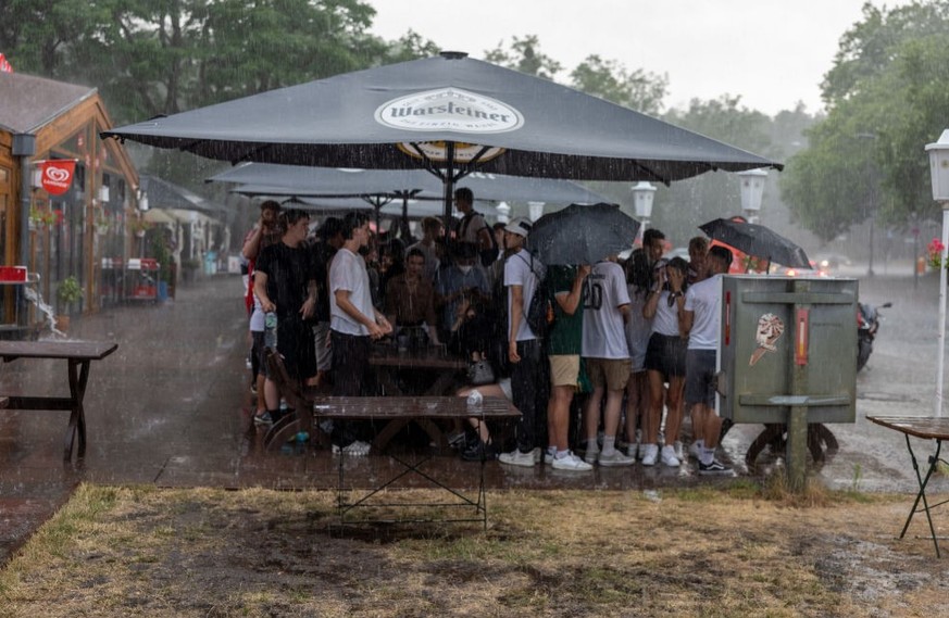 BERLIN, GERMANY - JUNE 29: Fans wait outside under after leaving a beer garden during heavy thunderstorm at the end of the game and score 2:0 for England on the UEFA EURO 2020 Round of 16 match betwee ...