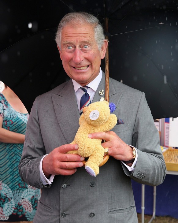 KING&#039;S LYNN, ENGLAND - JULY 31: Prince Charles, Prince of Wales is presented with a teddy bear for Prince George of Cambridge during a visit to the 132nd Sandringham Flower Show at Sandringham Ho ...