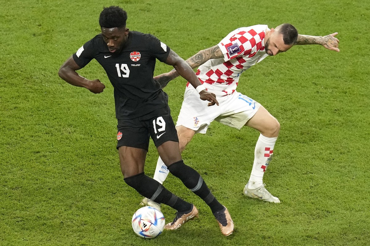 Canada's Alphonso Davies, left, and Croatia's Marcelo Brozovic, right, fight for the ball during the World Cup group F soccer match between Croatia and Canada, at the Khalifa International S ...