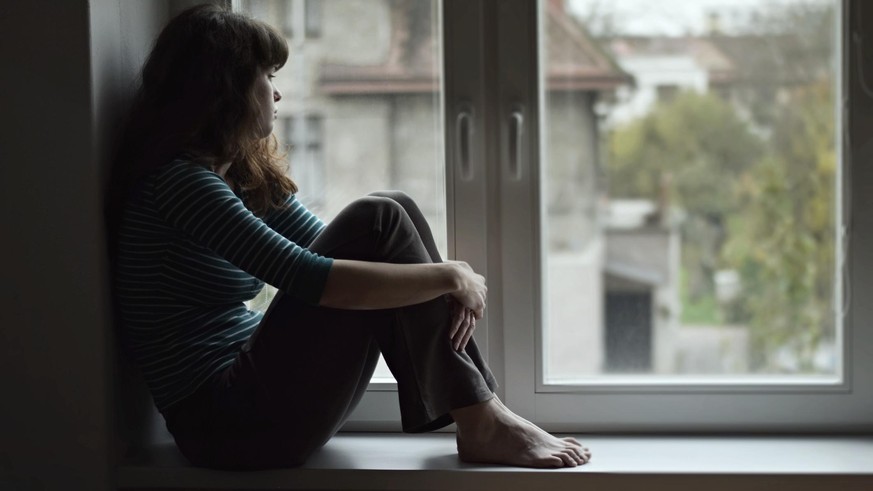 Traurige Frau sitzt am Fenster.