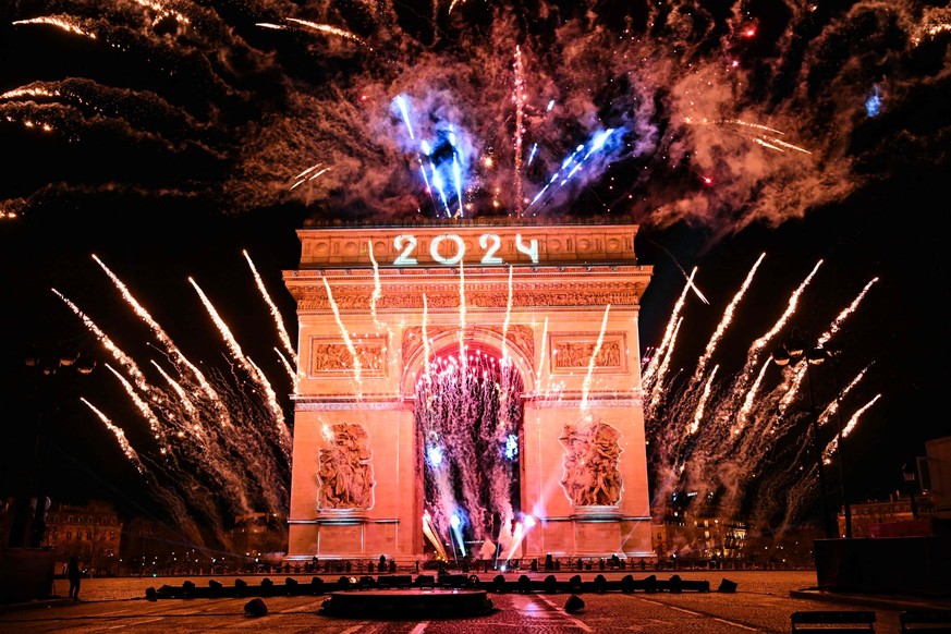 01.01.2024, Frankreich, Paris: Ein Feuerwerk explodiert neben dem Arc de Triomphe mit der Projektion &quot;2024&quot; auf der Avenue des Champs-Elysees w
