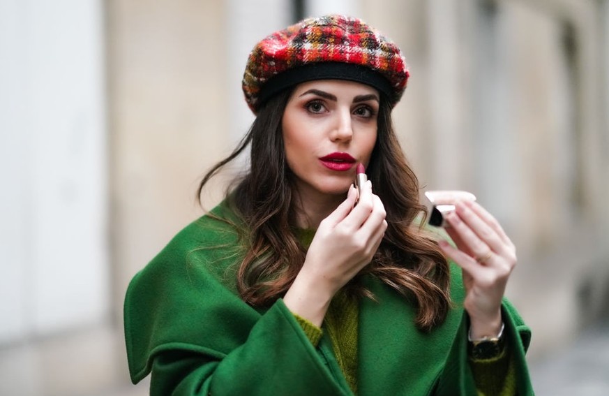 PARIS, FRANCE - NOVEMBER 11: Sara Carnicella wears a green long coat with large oversized lapels from Natan, a green wool pullover from Natan, a red checked wool beret hat from Anthony Peto, a golden  ...