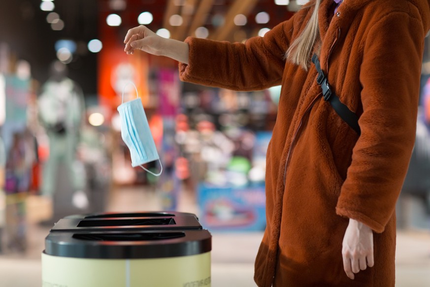 Woman throws a medical mask into the trash