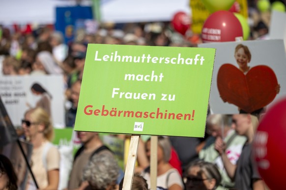 16.09.2023, Nordrhein-Westfalen, Köln: Demonstranten, die gegen Abtreibungen und assistierten Suizid sind, halten bei der Kundgebung ein Schild mit der Aufschrift «Leihmutterschaft macht Frauen zu Geb ...