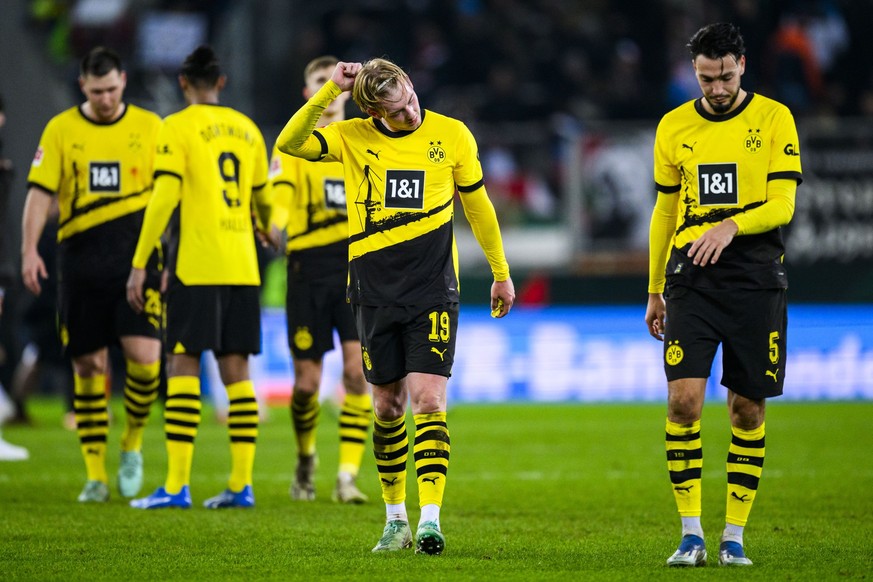 16.12.2023, Bayern, Augsburg: Fußball: Bundesliga, FC Augsburg - Borussia Dortmund, 15. Spieltag, WWK-Arena. Dortmunds Julian Brandt (2.v.r) und Dortmunds Ramy Bensebaini (r) reagieren nach dem Spiel  ...