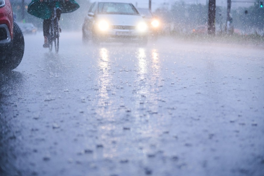 ARCHIV - 26.08.2022, Berlin: Autos fahren bei starkem Regen durch tiefe Pf