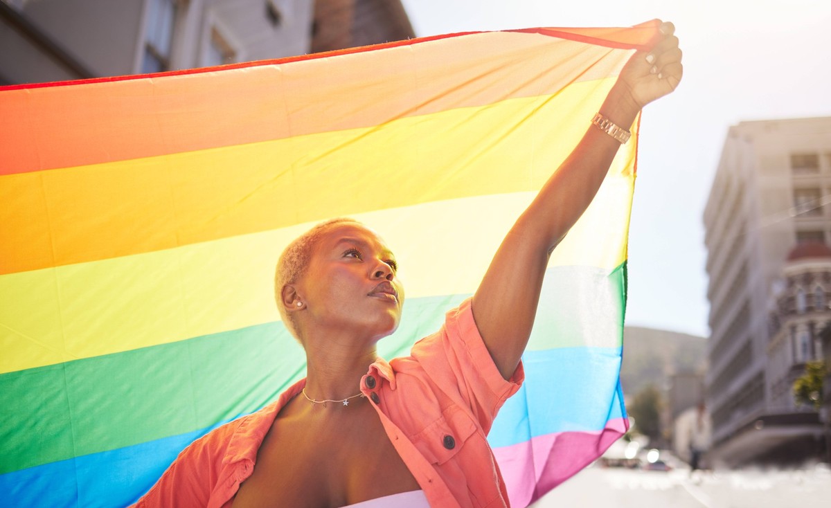 Lesbian, pride and black woman in city with flag for lgbtq community, ally or gay with support and equality in love outdoor. Rainbow, parade and lgbt awareness, inclusion and celebrate with sexuality  ...