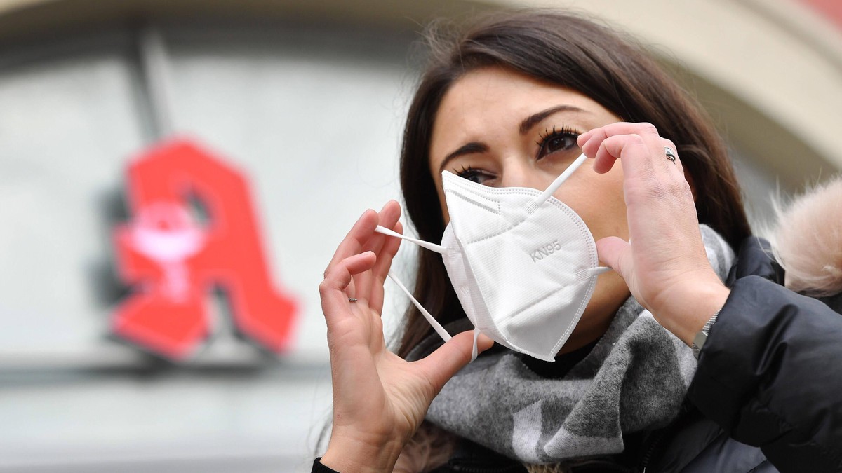 Bayern fuehrt FFP2-Maskenpflicht fuer Nahverkehr und Geschaefte ein. Archivfoto: Themenbild Coronavirus Pandemie im Herbst / Winter-Junge Frau legt eine KN95 Maske an. Mundschutz,Maske. Im Hintergrund ...