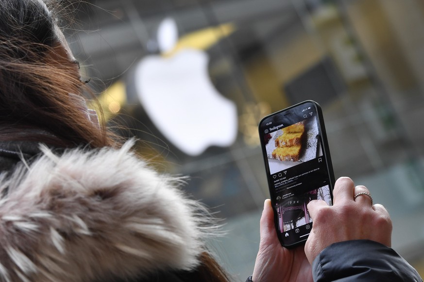 Maskenpflicht in den Fussgaengerzonen und oeffentlichen Plaetzen in Muenchen am 16.11.2020. Junge Frau mit Alltagsmaske blickt auf ihr Apple Iphone 12 PRO ,Instagram,soziale Netzwerke-im Hintergrund i ...