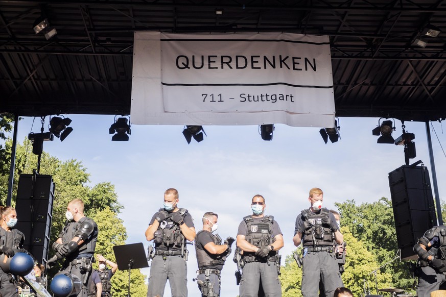 01.08.2020, Berlin: Polizisten stehen bei einer Kundgebung gegen die Corona-Beschränkungen auf der Straße des 17. Juni auf der Bühne unter dem Banner der Initiative «Querdenken 711». Die Polizei hat d ...