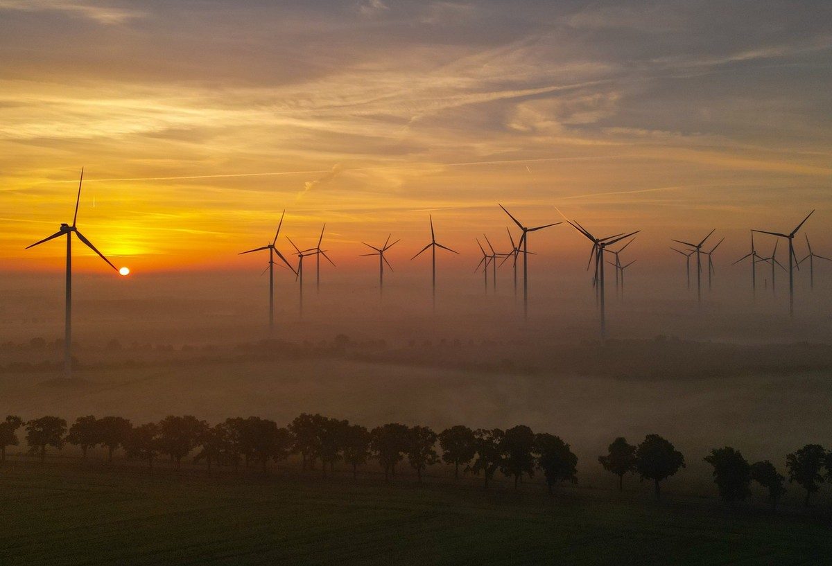 ARCHIV - 25.09.2023, Brandenburg, Sieversdorf: Der Sonnenaufgang scheint durch den Morgennebel �ber dem Windenergiepark �Odervorland�. (Luftaufnahme mit einer Drohne) (zu dpa �Windkraft an Land�) Foto ...