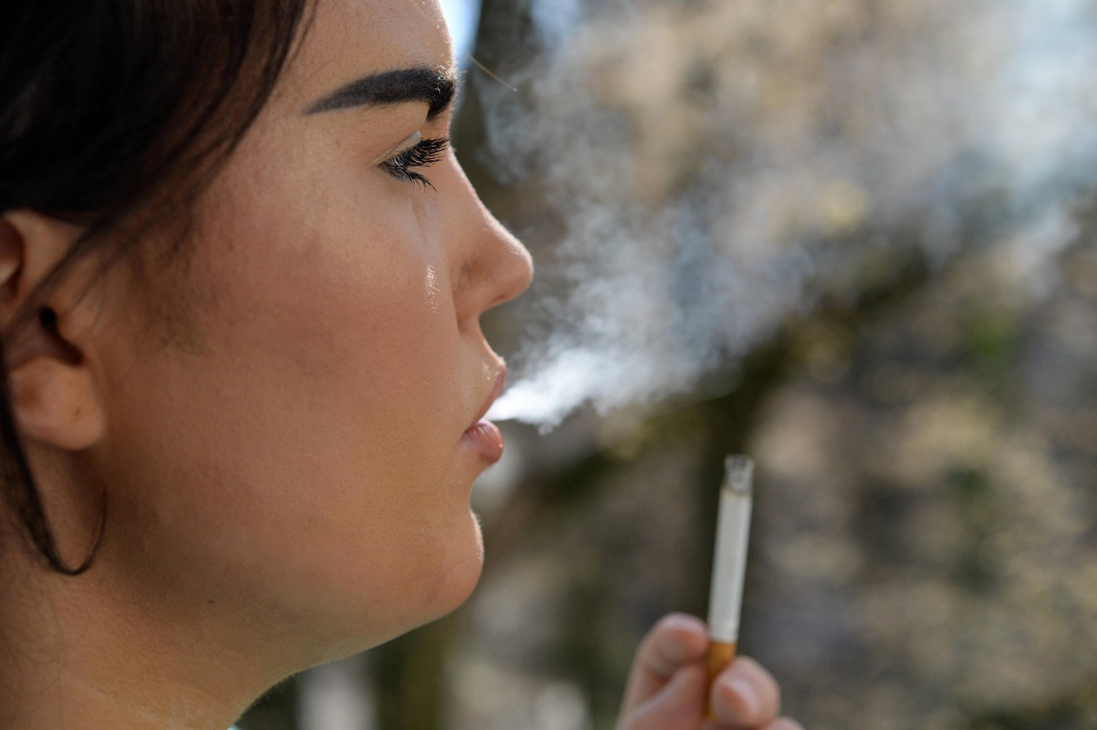 Junge Frau raucht eine Zigarette. Gerade jetzt bei der Coronavirus-Pandemie sind Raucher st