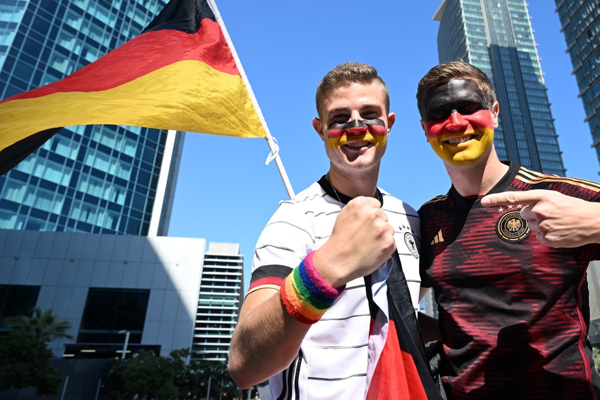 23.11.2022, Katar, Doha: Fußball, WM 2022 in Katar, die Deutschland-Fans Bengt (l) und Jan Kunkel stehen bei der Mobilen Fan-Botschaft des DFB in Doha. Bengt Kunkel wurde ein Regenbogen-Armband in ein ...