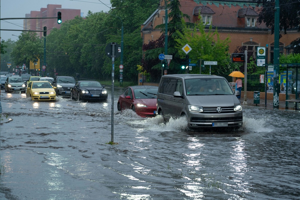 22.05.2024, Brandenburg, Potsdam: Autos fahren im Schritttempo durch die überflutete Zeppelinstraße. Starkregen hat am späten Nachmittag in Potsdam die Kreuzung Zeppelinstraße/Geschwister-Scholl-Straß ...