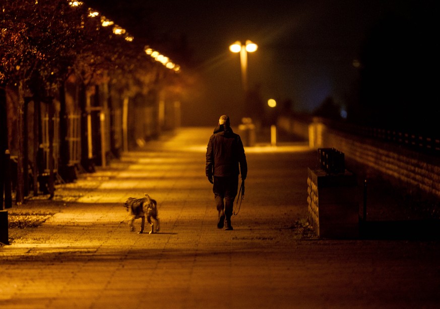 A man walks his dog in the outskirts of Frankfurt, Germany, Wednesday, Dec. 16, 2020, the first day of a nationwide lockdown. (AP Photo/Michael Probst)