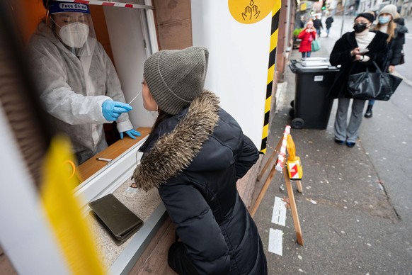 Eine Mitarbeiterin führt an einer Teststation, die sich in einem Café befindet und in der sich Passanten durch ein Fenster testen lassen können, einen Corona-Schnelltest an einer Frau durch. Beim Rest ...