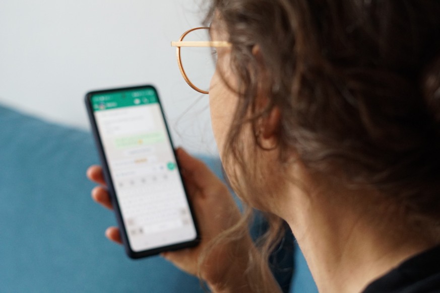 PRODUKTION - 29.09.2023, Berlin: Eine junge Frau hält ihr Smartphone in der Hand und liest eine Whatsapp-Nachricht. (zu dpa: «WhatsApp vermehrt von Unternehmen für Bewerbungen genutzt») Foto: Weronika ...