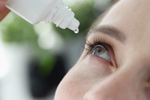 Woman dripping into her eyes with antibacterial drops closeup. Treatment of viral conjunctivitis concept