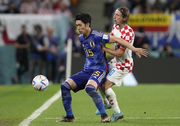 Japan's Daichi Kamada, left, challenges for the ball with Croatia's Luka Modric during the World Cup round of 16 soccer match between Japan and Croatia at the Al Janoub Stadium in Al Wakrah, Qatar, Mo ...