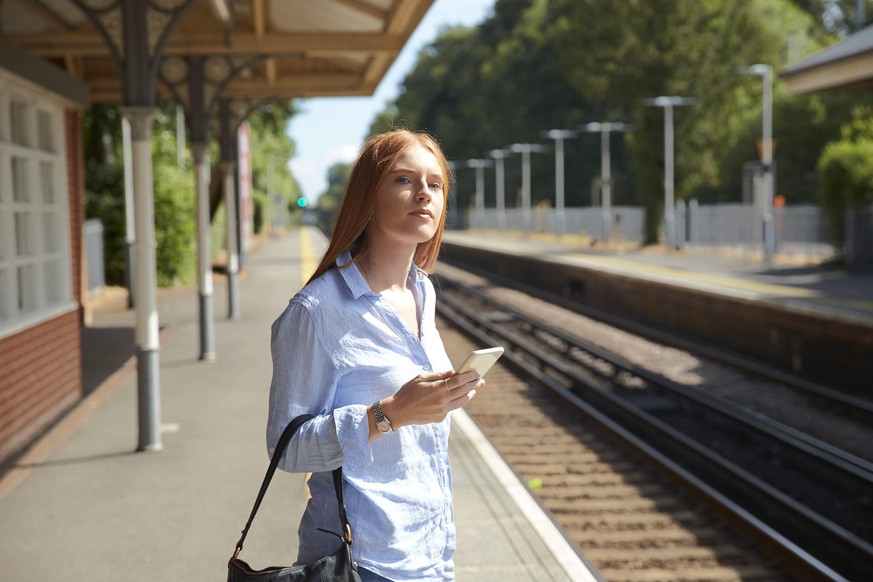 Eine Frau steht an einem Bahnhof. Wegen des schlechten Netzausbaus wird sie auf dem Land wohl kein 5G-Netz haben.