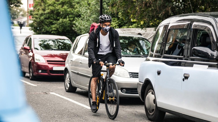 Cyclist commuter wearing a pollution-mask in Central London, while commuting to work in the morning.