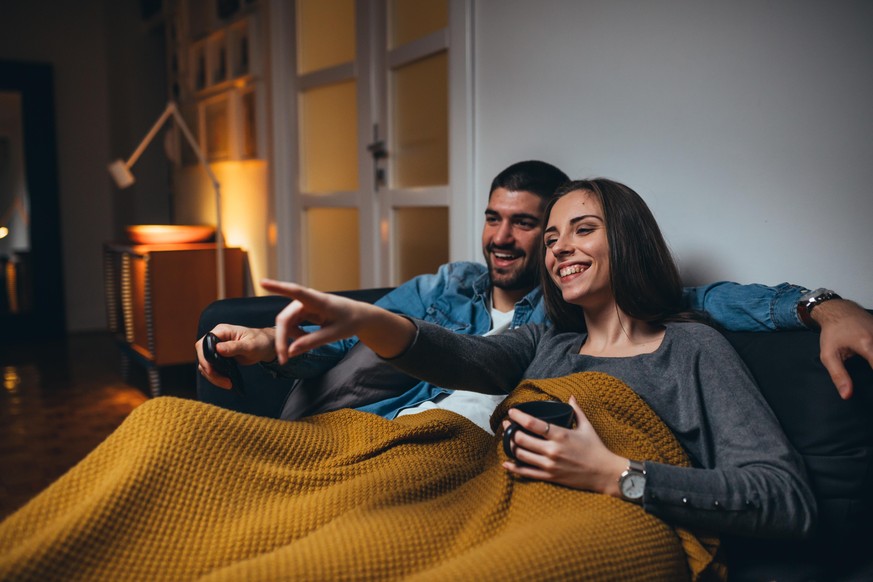 romantic couple watching television at home