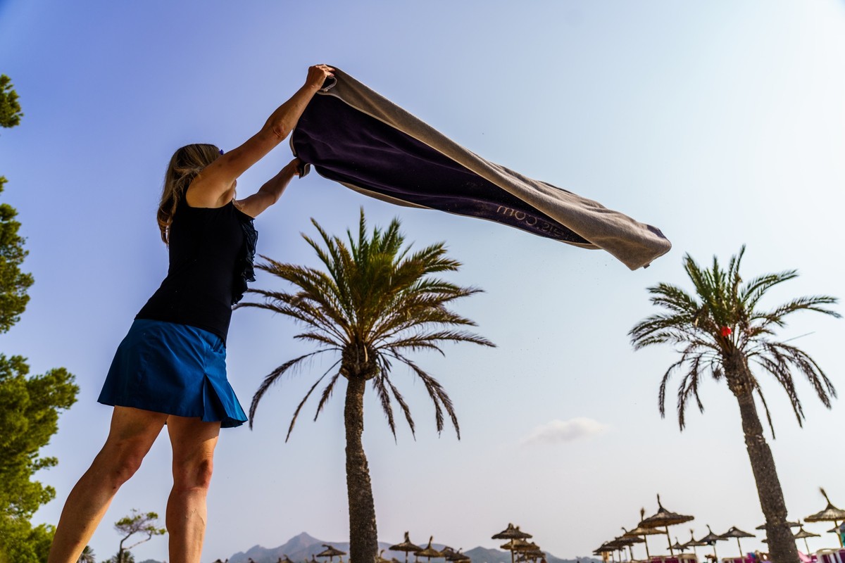 ARCHIV - 26.09.2021, Spanien, Alcudia: Eine Frau breitet am Strand von Alcudia ihr Handtuch aus. Endlich wieder Urlaub mit Strand und Pool. Hotels sind voll und damit kehren Unsitten zur