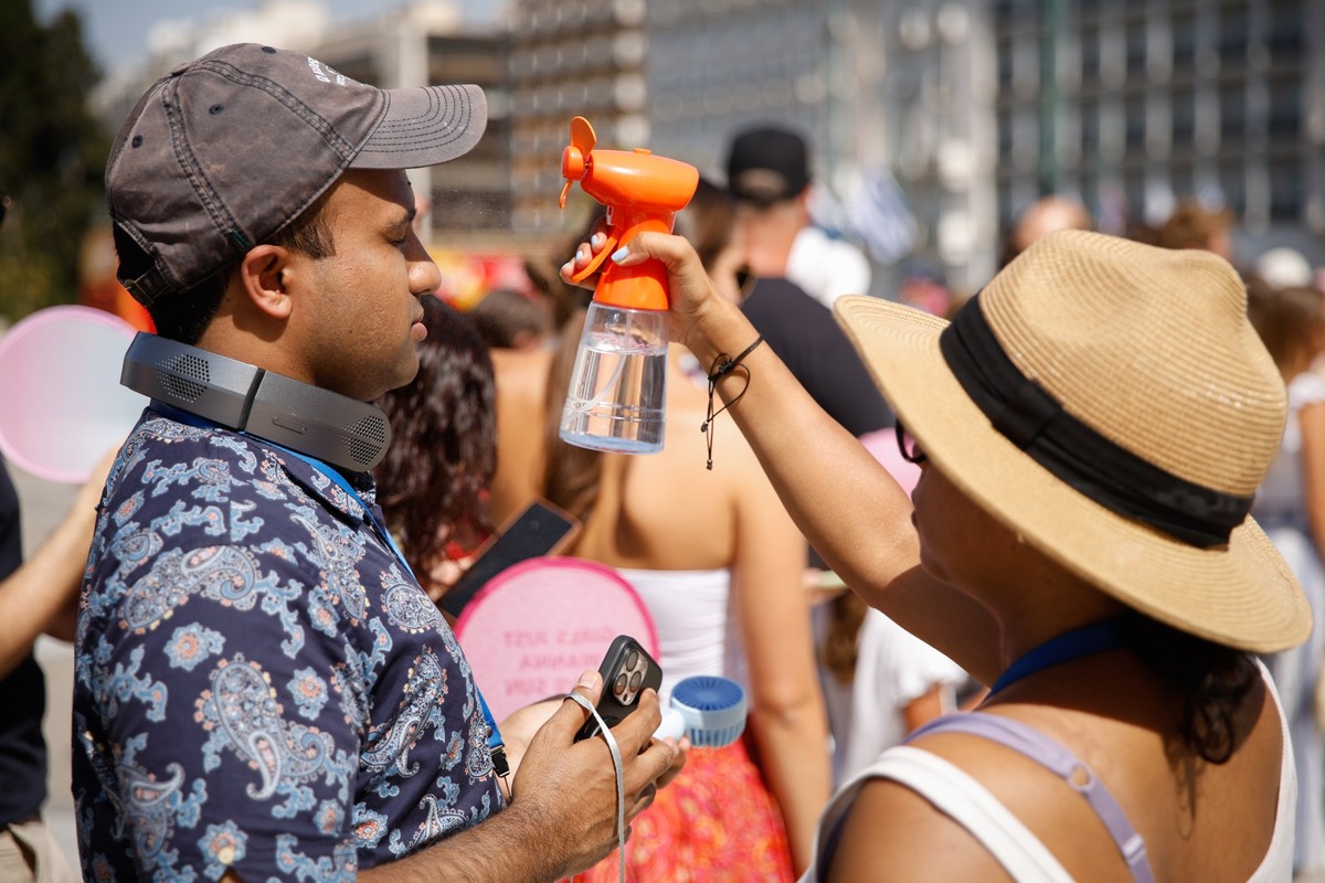 23.07.2025, Griechenland, Athen: Touristen stehen vor dem griechischen Parlament im Zentrum Athens und leiden unter der Hitze. Eine Hitzewelle mit Temperaturen von über 40 Grad macht den Menschen in w ...