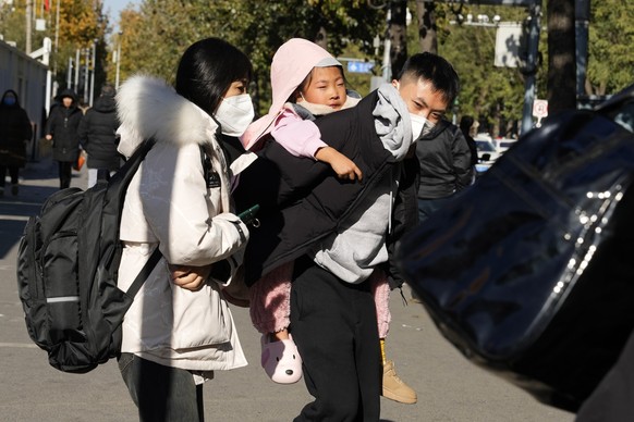 A man carries a child as they leave a children&#039;s hospital in Beijing, Friday, Nov. 24, 2023. Chinese officials say they did not detect any &quot;unusual or novel diseases&quot; in the country, th ...