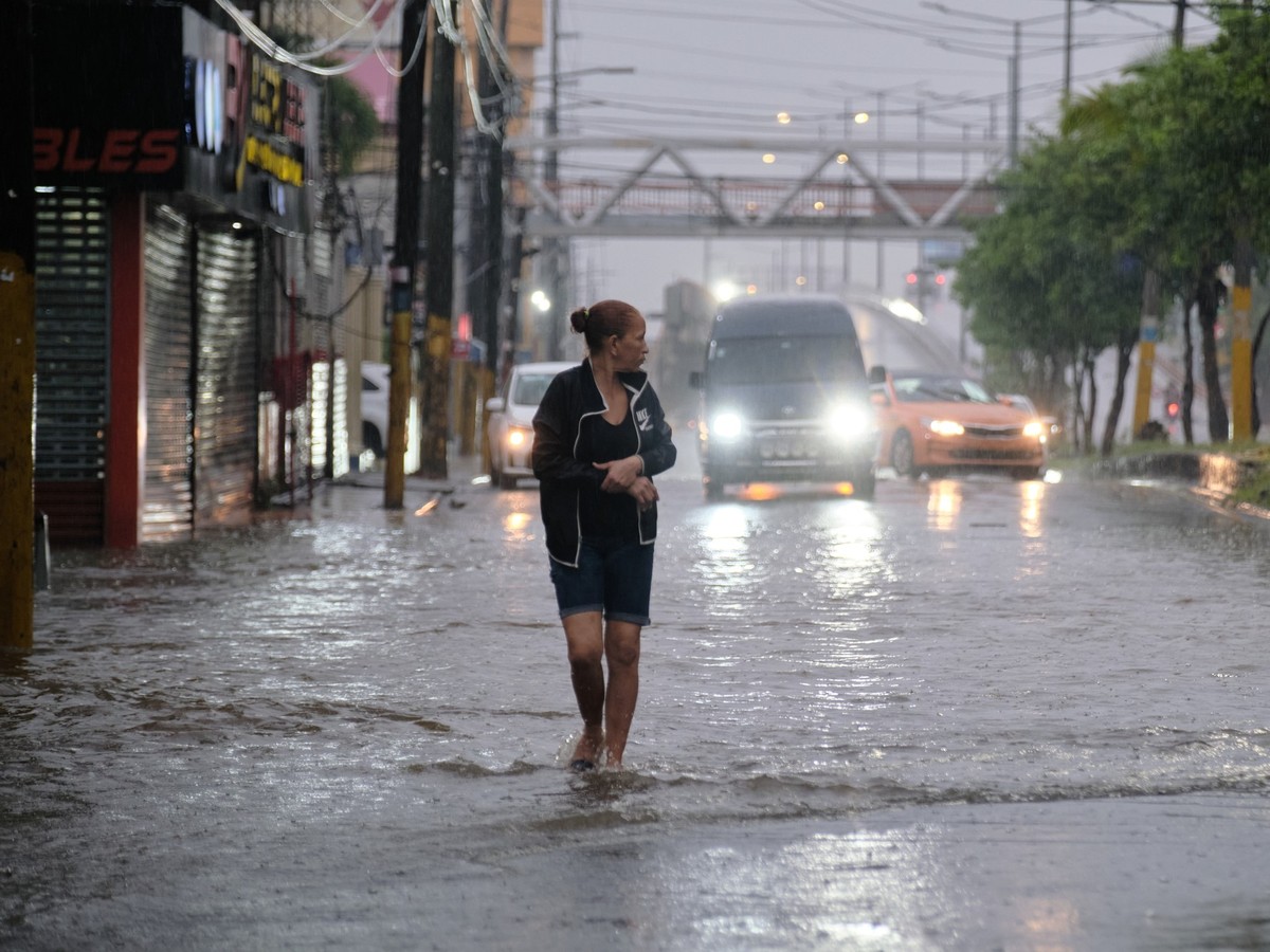 24.10.2025, Dominikanische Republik, Santo Domingo: Eine Frau geht in Santo Domingo durch eine Straße, die von den Regenfällen des Tropensturms Melissa überflutet wurde. Foto: Ricardo Hernandez/AP/dpa ...
