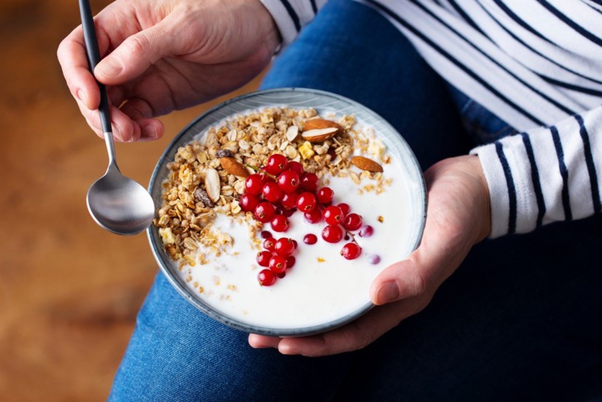Woman&#039;s hands holding healthy breakfast bowl. Yogurt, granola, muesli, fresh berries
