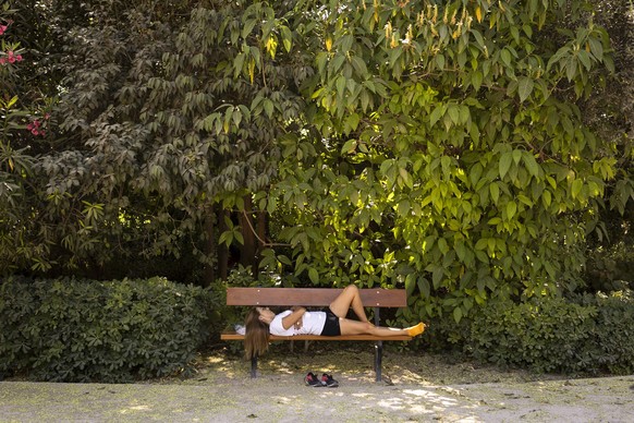 18.06.2024, Griechenland, Athen: Eine Frau ruht sich auf einer Bank im Schatten im Nationalgarten aus. Griechenland ist in diesem Jahr besonders früh von großer Hitze betroffen: Meteorologen zufolge w ...