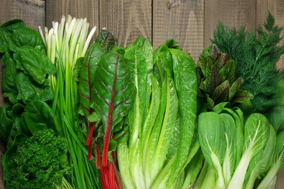 Spring vitamin set of various green leafy vegetables on rustic wooden table. Top view point.