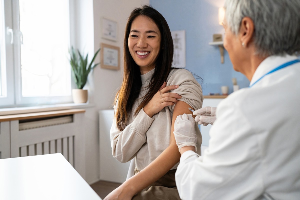 Senior Caucasian female doctor, giving an flu vaccine to a female patient Japanese ethnicity, during an annual medical check-up